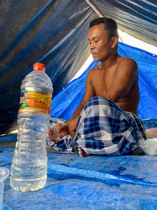 Un homme et sa bouteille en plastique sous une tente