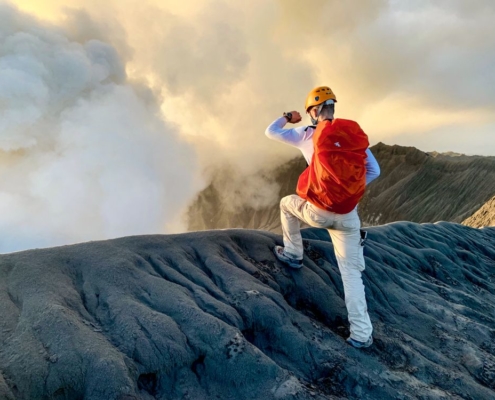 Un alpiniste regarde au fond d'un cratère qui fume