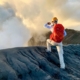 Un alpiniste regarde au fond d'un cratère qui fume