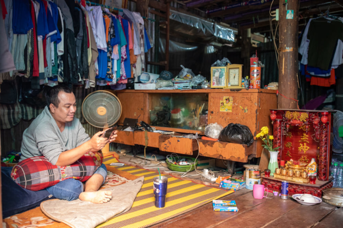 Un cambodgien utilise son téléphone sous une garde robe