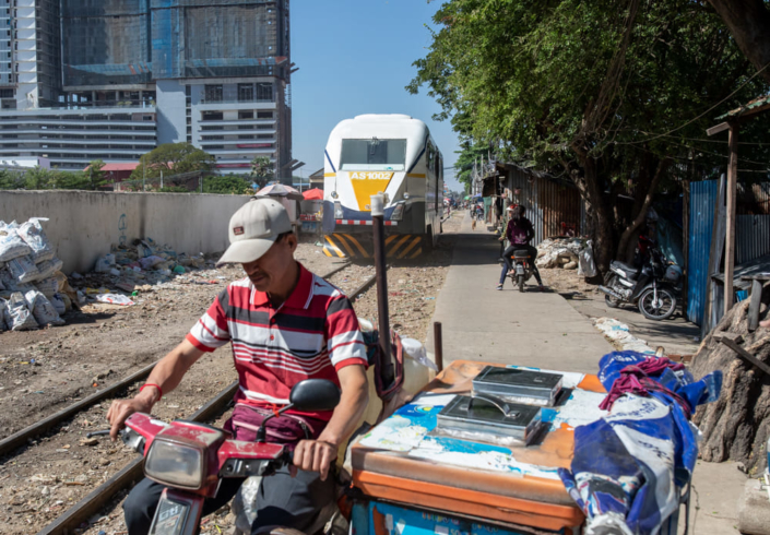 Photo reportage sur la vie dans un bidonville cambodgien. Trains et vendeurs ambulants se frôlent