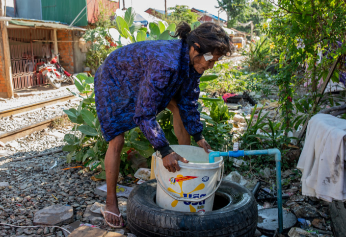 Une femme asiatique remplit un seau d'eau