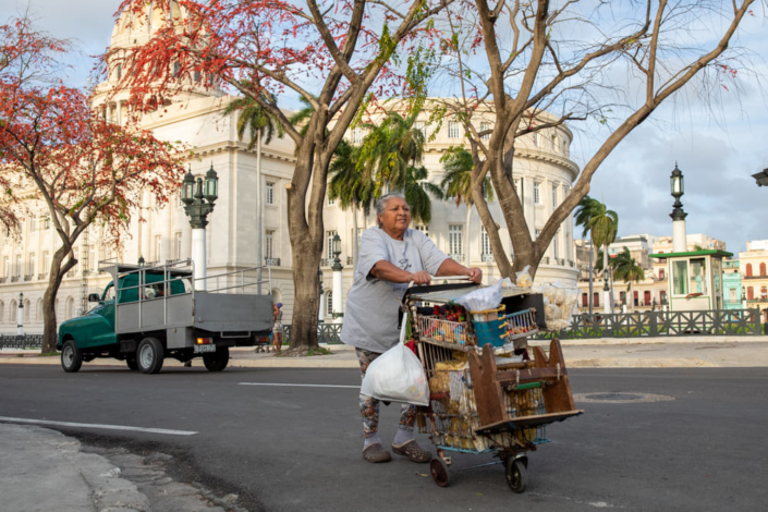 Une femme pousse un chariot dans une rue de la Havane, face au capitole