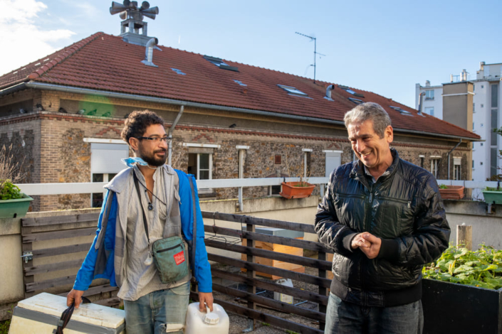 Deux apiculteurs sur un toit sourient pour une photographie artistique.