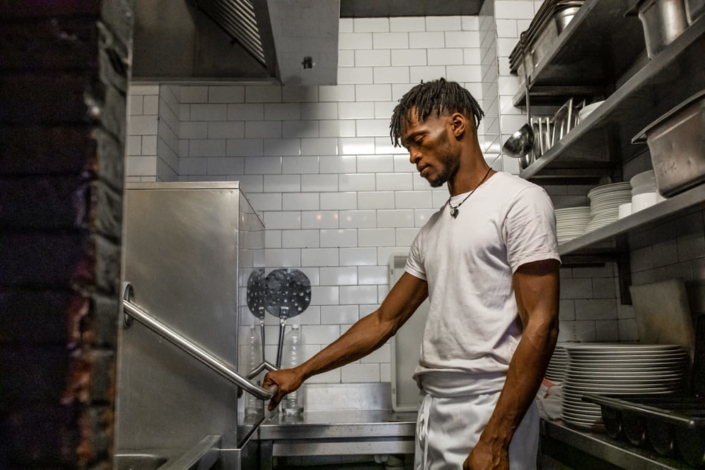 Un migrant travaille dans la cuisine d'un restaurant.