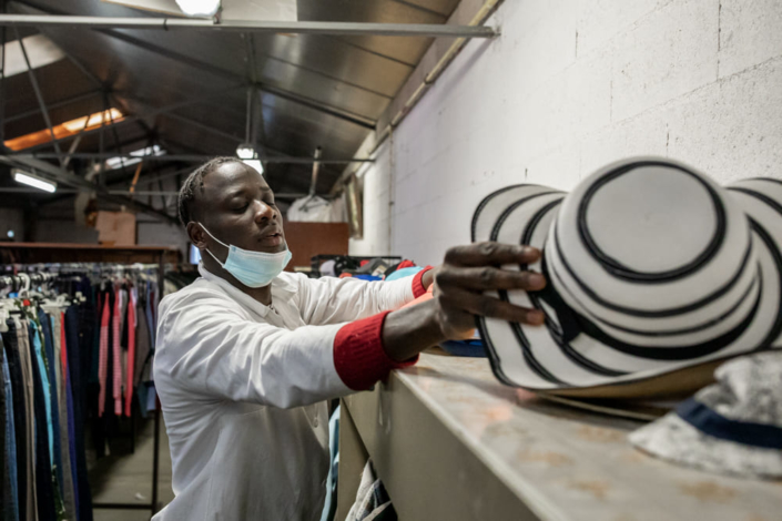 Un migrant trie des chapeaux.