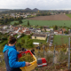 Au sommet d'un terril un homme porte une caisse de raisin. Vue sur le vignoble et sur la cité minière de Haillicourt