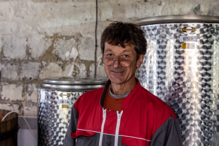 Portrait d'un vigneron devant des cuves