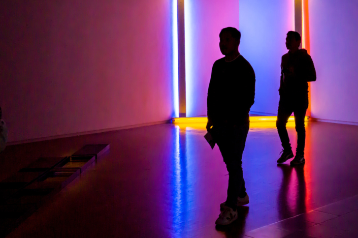 Silhouettes de visiteurs admirant une peinture lumineuse faite en néons