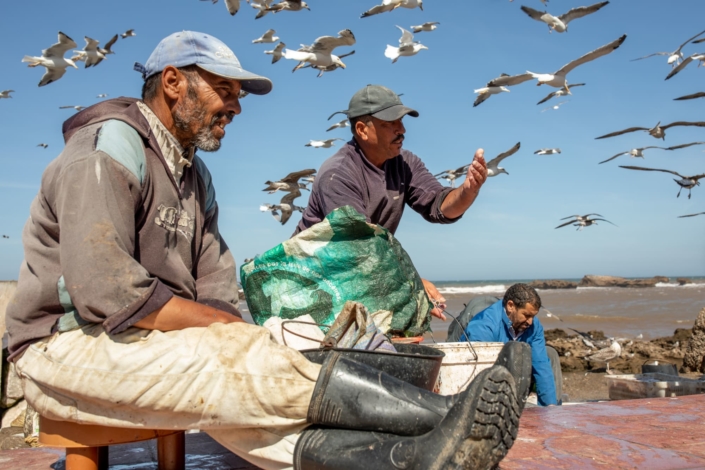 Trois pêcheurs sous une nuée de mouette