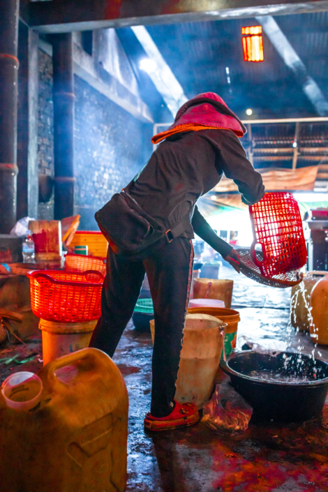 Une femme Khmer verse de l'eau. La photographie est prise à contre jour pour mettre en valeur les couleurs vives