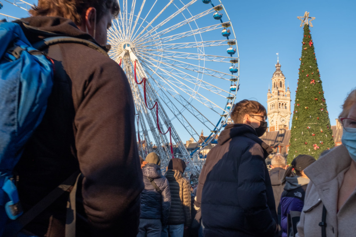 Foule sur la place de Lille, grande roue et beffroi en arrière plan