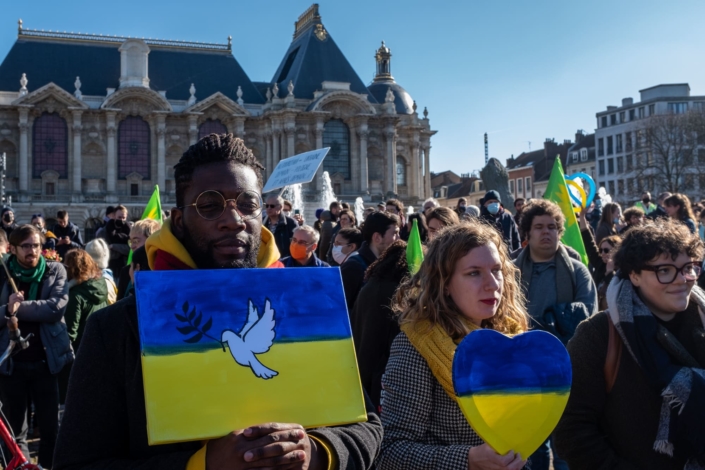 Un homme tient une peinture du drapeau ukrainien avec une colombe. Une femme tient un coeur bleu et jaune