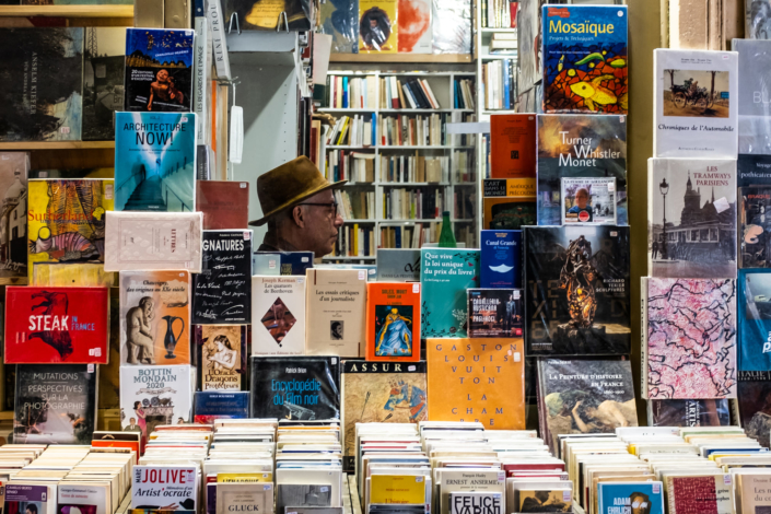 Tete d'un homme portant un chapeau au mileu de livres