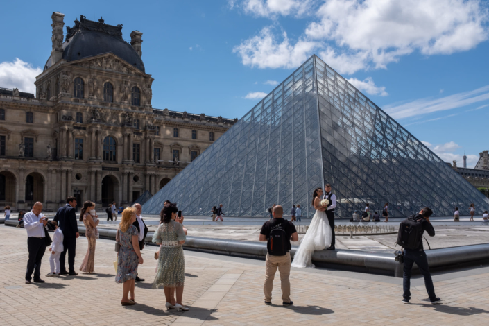 Tres rares touristes autour de la pyramide du Louvre. Un couple de maries en profite pour faire les photos de mariage