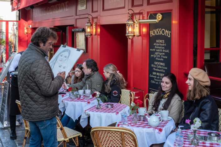 Un artiste de rue dessine deux clientes assises à une terrasse de la place du Tertre à Montmartre