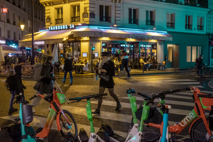 Illustration de nombreuses trottinettes stationnées de nuit dans une rue parisienne