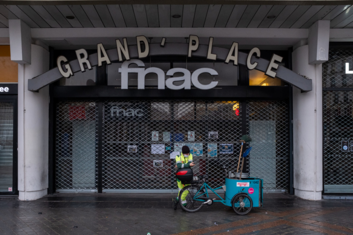 Entrée de la FNAC, les rideaux sont baissés, un balayeur se repose