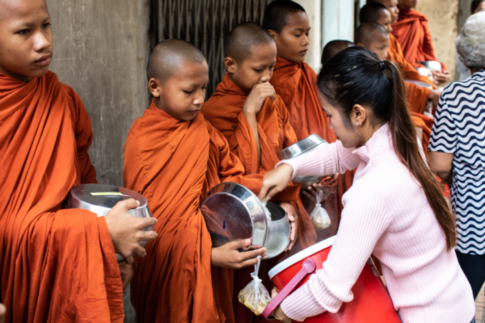 Une femme donne à manger aux enfants moines du Cambodge