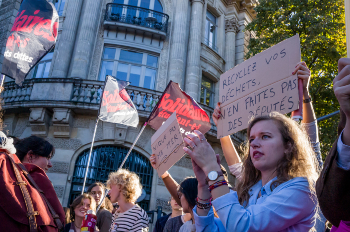 Manifestants levant des pancartes parlant de l'écologie et des députés