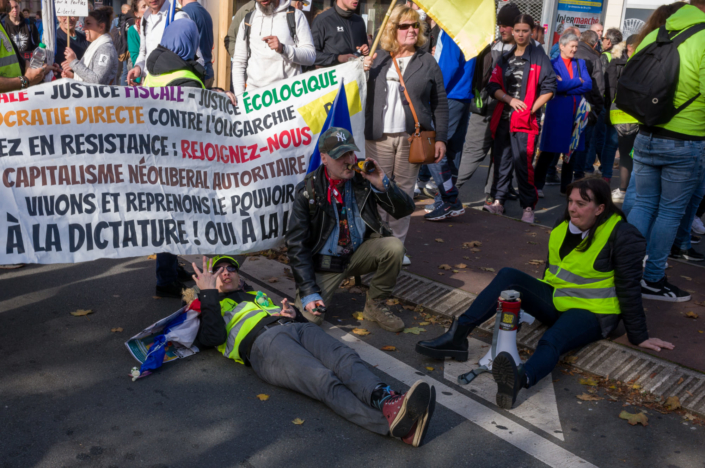 Photographie de gilets jaunes assis sur le sol manifestent contre pouvoir d'achat et inflation