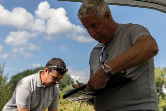 Un homme inscrit des données sur une fiche. Vue en contre plongée.