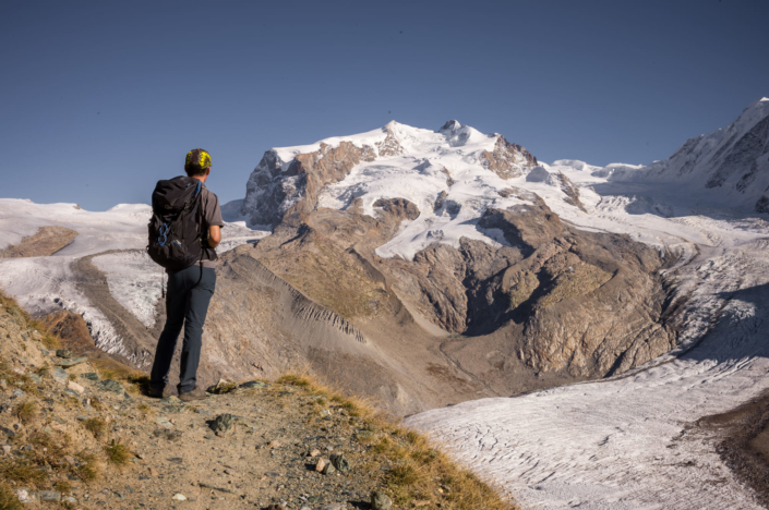 Un randonneur observe la fonte d'un glacier au pied du Mont Rose