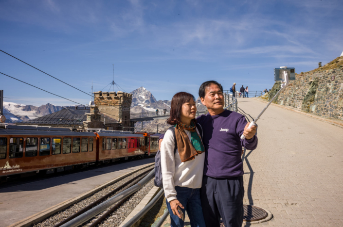 Deux touristes asiatiques font un selfie dans une gare de montagne