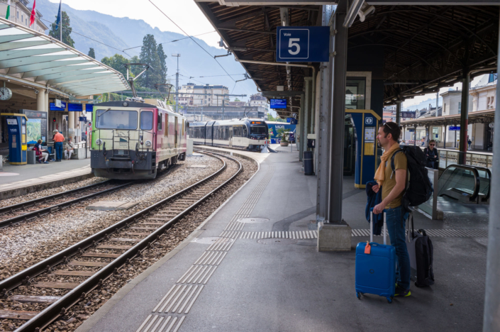 Photo de train dans une gare. Un voyageur attend