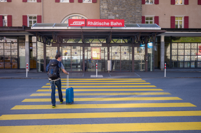 Un voyageur tire sa valise sur un passage piéton pour entrer dans la gare de Lucerne