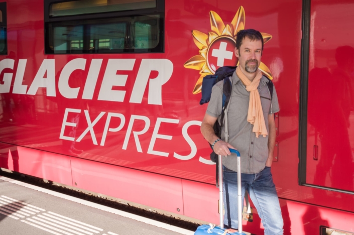 Portrait d'un touriste devant un train rouge (glacier express )