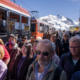 Une foule sur le quai de la gare longe un train . Montagnes en arrière plan