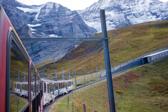 Photo d'un train sortant d'un tunnel sous les montagnes enneigées