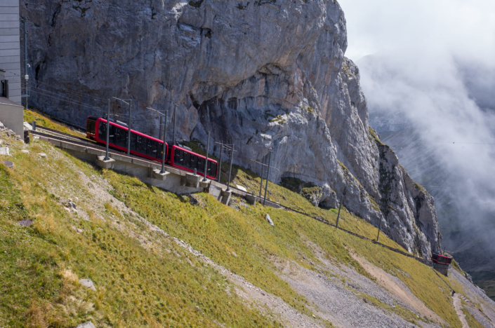 Un train à crémaillère grimpe le long de parois rocheuses dans le brouillard